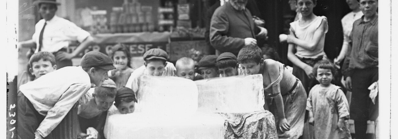 Kinderen likken een blok ijs op een warme dag in 1910