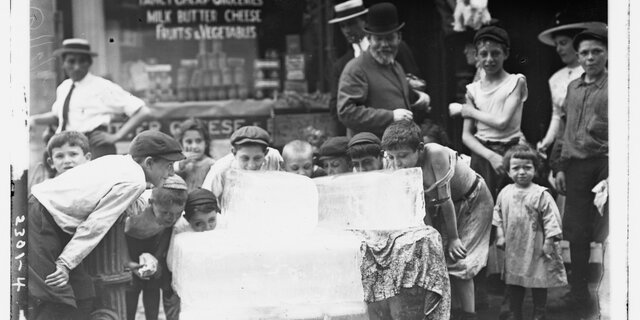 Kinderen likken een blok ijs op een warme dag in 1910